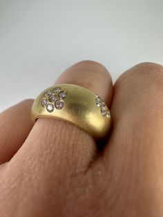 a close up of a person's hand wearing a gold ring with diamonds on it