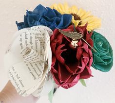 a close up of a person's hand holding a paper flower