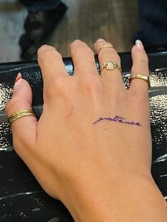 a woman's hand with a tattoo on her left wrist and the word love written in purple ink