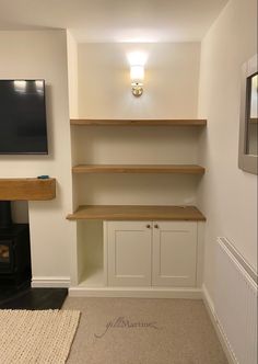 an empty room with some shelves and a tv mounted on the wall above it in front of a fire place