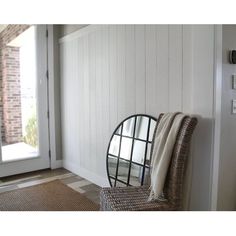 a chair sitting in front of a white wall with a round mirror on it's back