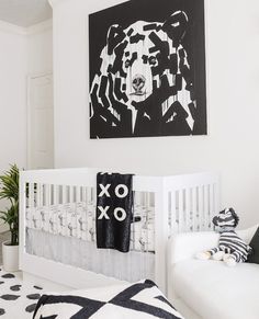 a baby's room with a white crib, black and white artwork on the wall