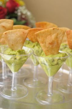 small glasses filled with guacamole and tortilla chips