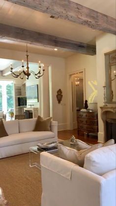 a living room filled with furniture and a fire place under a chandelier in front of a fireplace