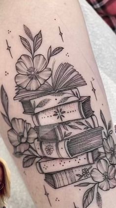 a woman's thigh with books and flowers on it