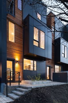 a modern house with stairs leading up to the front door and side windows on both sides