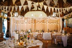 a banquet hall with tables and chairs set up for a formal function, decorated with white linens hanging from the ceiling