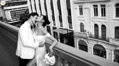 a bride and groom kissing on a balcony