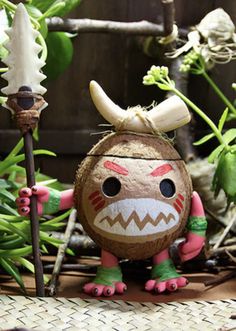 an odd looking toy in the middle of some plants with horns on it's head