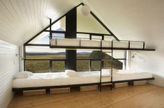 bunk beds in a room with white walls and wood flooring, along with large windows that look out onto the countryside