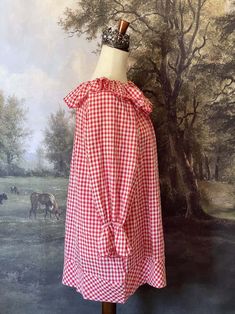 This charming Red Gingham Tunic Dress is perfect for cozy cottage mornings with it's historically-inspired features, such as a playful scalloped ruffle collar, scalloped ruffle bishop sleeves, an A-line silhouette, and wide hem. Wear it alone, or as a chemise for a full victorian-inspired outfit! This piece is a product sample that we did not order more of, and thus stock is limited to one! Sizing: Fits like an L-XLBust - up to 48 Inches / 125 CentimetersWaist - up to 48 Inches / 125 CentimetersLength - 31 Inches / 78 CentimetersSleeve Length - 21.5 Inches / 54 CentimetersSleeve Width - 19 Inches / 48 Centimeters Condition:A+ | New without tags. Product sample. Materials:100% Cotton Long Sleeve Ruffled Dress For Picnic, Gingham Dress With Ruffles For Daywear, Plaid Puff Sleeve Dress With Ruffles, Gingham Ruffled Dress For Daywear, Gingham Ruffle Dress For Daywear, Cottagecore Gingham Dress With Ruffles, Fantasy Shop, Countryside Cottage, Medieval Fashion