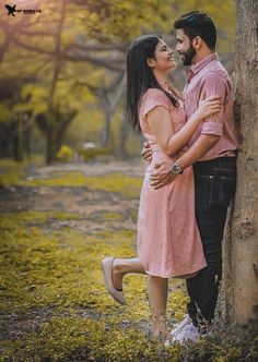 a man and woman standing next to each other near a tree