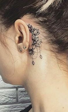 a woman's behind the ear has a flower tattoo on it