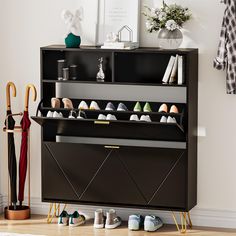 a black cabinet with shoes and umbrellas on it in front of a white wall