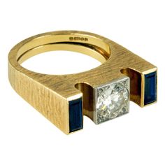 A brilliant-cut diamond, baguette-cut sapphire, and 18-karat gold ring by Andrew Grima, 1977. This stylish ring, which is a size 07¼, would make a perfect non-traditional engagement ring for the design-minded person. The ring also has an impecable pedigree. It is signed Grima, Stamped AGLtd, and has London hallmarks with the date letter "c" for 1977. Andrew Grima was arguably the most important, innovative avant-garde London jeweler who transformed the jewelry scene of the 1960s and 1970s in Eng Andrew Grima, Traditional Engagement Rings, Isabel Ii, Stylish Rings, Letter C, Alternative Engagement Rings, 18k Yellow Gold Ring, Victoria And Albert Museum, Three Stone Rings