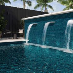 an outdoor swimming pool with blue tiles and water features waterfall casing down the side