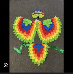 three colorful kites sitting on the ground next to each other with ribbons around them