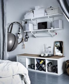 a bedroom with white walls and shelves filled with items