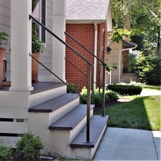 the front steps of a house with potted plants on each side and an iron hand rail