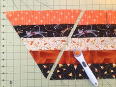 the scissors are laying next to an orange and black piece of fabric that has been cut into triangles