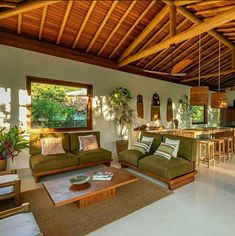 a living room filled with furniture and a wooden ceiling over a dining area next to a kitchen