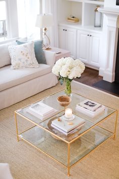 a living room with a couch, coffee table and books on the floor in front of a fireplace