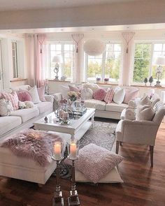 a living room filled with lots of furniture and pink pillows on top of it's couches