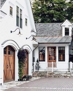 a white house with two brown doors and brick walkway leading up to the front door