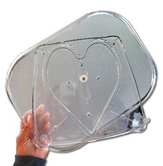 a person is holding up a heart shaped tray with two holes in the middle and one hole at the top