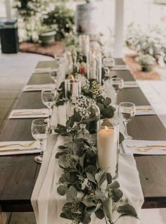 a long table with candles and greenery on it