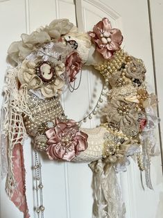 a wreath is hanging on the door with pearls and laces around it's edges