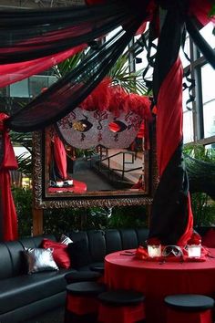 a red and black wedding set up in a room with couches, tables and chairs