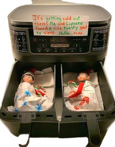 two baby dolls sitting in the bottom of an air fryer with writing on it