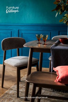 three chairs and a table in front of a blue wall