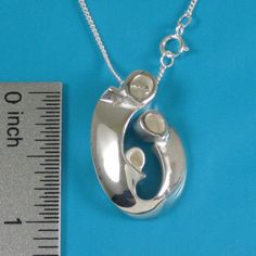 "Mother of two children pendant may also be interpreted as celebrating your family of three! Our expressive, egg-shaped creation is hand sculpted in sterling silver. Size: 1\" X 3/4\": $145. Bright polished heads and raised curves are contrasted with recessed contours that have a soft satin finish. Fully finished reverse. This dimensional pendant includes a sterling chain that threads through the design's integrated and invisible chain bail. The included US-made 1.2mm curb link chain with spring Sterling Silver Oval Pendant Necklace As Gift For Mom, Sterling Silver Oval Necklace For Mom, Oval Sterling Silver Necklace For Mom, Mother's Day Polished Sterling Silver Necklaces, Mother's Day Sterling Silver Polished Necklace, Sterling Silver Polished Necklace For Mother's Day, Sterling Silver Oval Pendant Necklace For Mother's Day, Sterling Silver Necklace With Polished Finish For Mother's Day, White Gold Sterling Silver Custom Necklace For Mother's Day