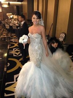 a woman in a wedding dress is walking down the aisle with her bouquet on her hand