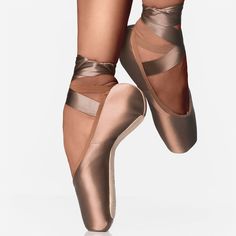 the legs and ankles of a ballerina in bronze ballet shoes, with straps on each side