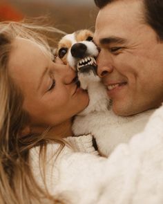 a man and woman are cuddling with a dog