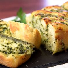 a piece of bread with spinach and cheese on it sitting on a black plate