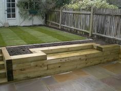 a wooden garden bench sitting on top of a patio next to a grass covered yard