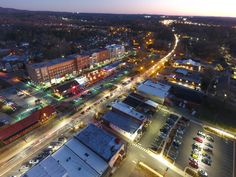 an aerial view of a city at night with cars parked on the street and buildings lit up