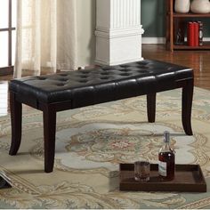 a black leather bench sitting on top of a rug