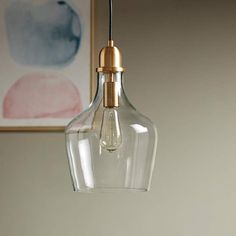 a clear glass light hanging from a ceiling fixture with a gold colored metal fittings