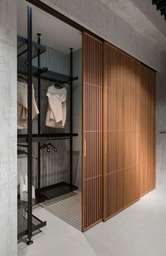 an open closet with clothes hanging on shelves