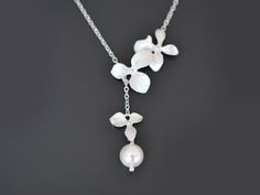 "** Free gift wrapping! - Each jewelry comes in Beautiful Gift Box! ** ** Free greeting card! - Please add your message on note box when you check out ** Orchid flower and Pearl Silver lariat necklace - Orchid necklace, Flower necklace, Pearl necklace, Silver necklace, Lariat necklace, Wedding jewelry, Bridal necklace, Anniversary   A gorgeous lariat made with white gold plated over brass orchid flowers and 8mm Swarovski pearl with white gold plated over a brass chain and clasp to finish this be Adjustable Flower Charm Necklace For Wedding, Adjustable Wedding Flower Necklace With Charm, Elegant Adjustable Flower Necklace For Wedding, Adjustable Flower Pendant Necklace For Wedding, Silver Flower Pendant Necklace For Wedding, Delicate Silver Lariat Necklace For Anniversary, Silver Pendant Flower Necklace For Wedding, Wedding Necklace With Adjustable Chain And Flower Pendant, Sterling Silver Bridal Necklace As Gift