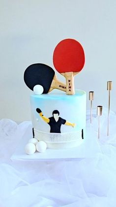 a cake decorated with ping pong paddles and balls on a white tablecloth