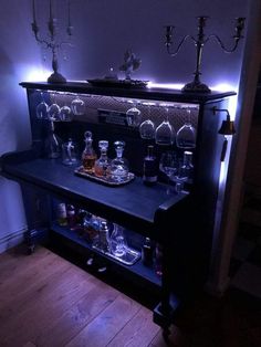 a shelf filled with bottles and glasses on top of a wooden floor next to a wall