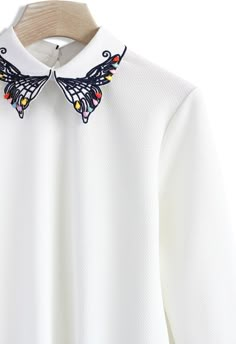 a white shirt with butterflies on the collar