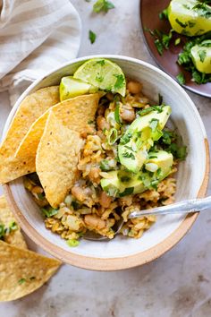 a bowl filled with rice, beans and veggies next to tortilla chips