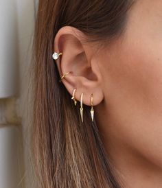 a close up of a person wearing gold ear cuffs with small spikes on the end